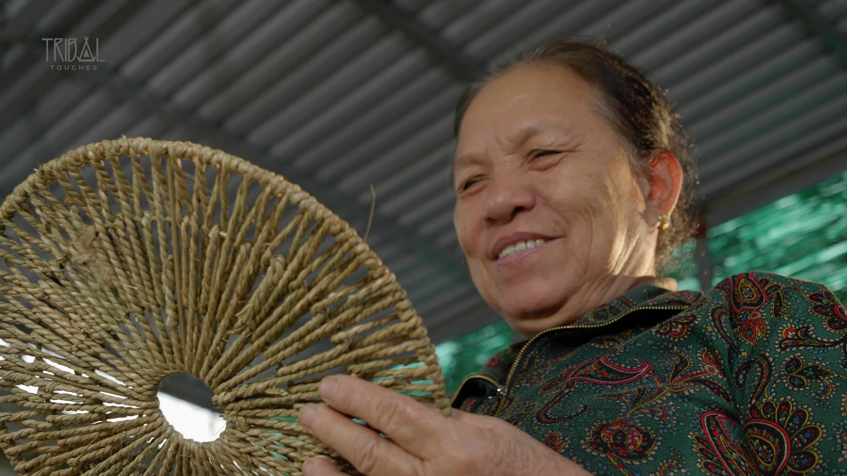 Smiling artisan holding a Tribal Touches handcrafted décor box with woven seagrass crafts.