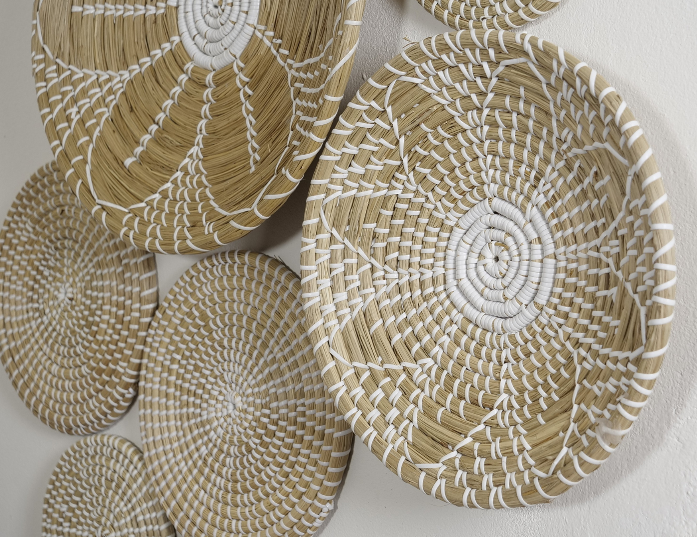 Close-up view of the Pure Elegance wall basket set showcasing fine craftsmanship and intricate white woven patterns on natural materials.
