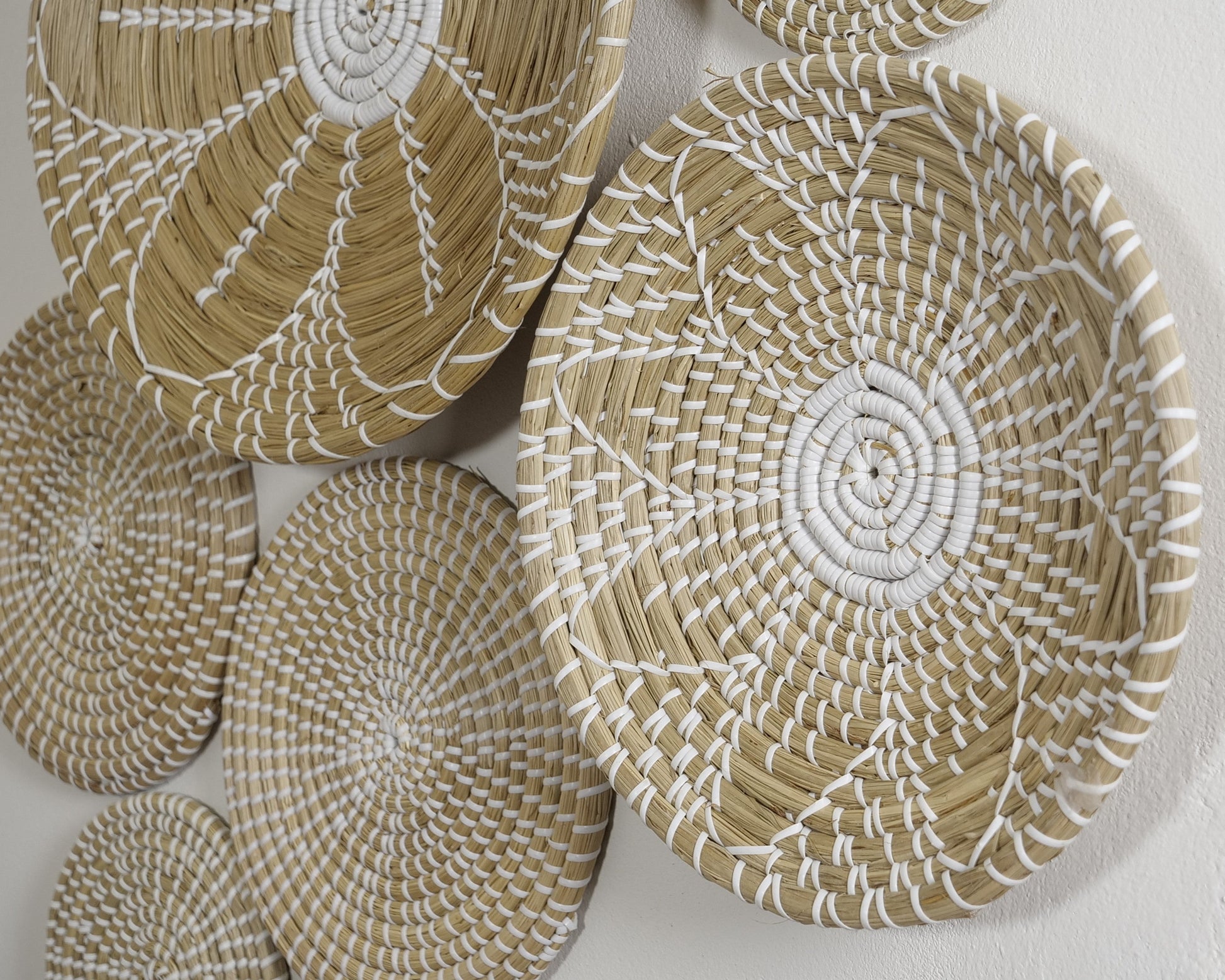 Close-up view of the Pure Elegance wall basket set showcasing fine craftsmanship and intricate white woven patterns on natural materials.